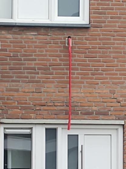 A red ribbon hanging down the wall of a house as a sign of drawing a red line.