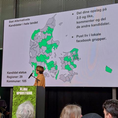 Toke Lotz taler. 

På baggrundsskærmen står der: 
Støt Alternativets kandidater i hele landet. 

* Del dine opslag på 2.0 (en Facebook gruppe) og like, kommenter og del de andre kandidater. 
* Pust liv i lokale Facebook grupper. 

Kandidat status:
Regioner: 29
Kommuner: 105

I midten af skærmen er der et Danmarks kort over kommunerne, hvor de kommuner der er kandidater i er grønne, og de kommuner der endnu ikke har kandidater er grå.

De kommuner der har kandidater er:
Thisted, Aalborg, Mariagerfjord, Viborg, Favrskov, Århus, Syddjurs, Skanderborg, Hedensted, Vejle, Billund, Esbjerg, Fanø, Tønder, Haderslev, Middelfart, Nordfyn, Assens, Odense, Nyborg, Holbæk, Lejre, Halsnæs, Gribskov, Helsingør, Fredensborg, Ruderdal, Lyngby-Taarbæk, Gladsaxe, Furesø, Egedal, Høje Taastrup, Glostrup, København, Frederiksberg, Køge, Stevns, Næstved, Langeland og Bornholm.