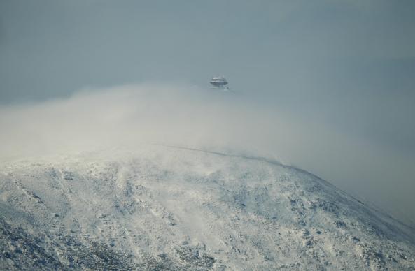 Majowy widok na zaśnieżoną Śnieżkę, częściowo przykrytą przez chmury