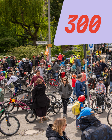 Große Gruppe von Radfahrern, darunter viele Kinder, versammelt warten am Weigandufer. Dazu die Zahl 300 in großer Schrift