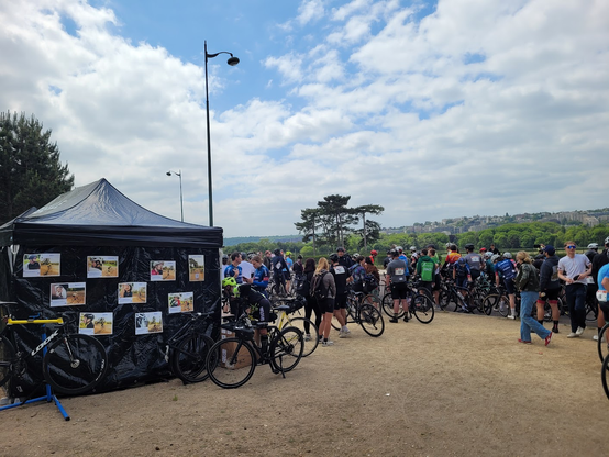 Camp de base aux 24hLongchamp : grande tente sur laquelle sont positionnées des photos, des vélos à droite à gauche, plein de cyclistes