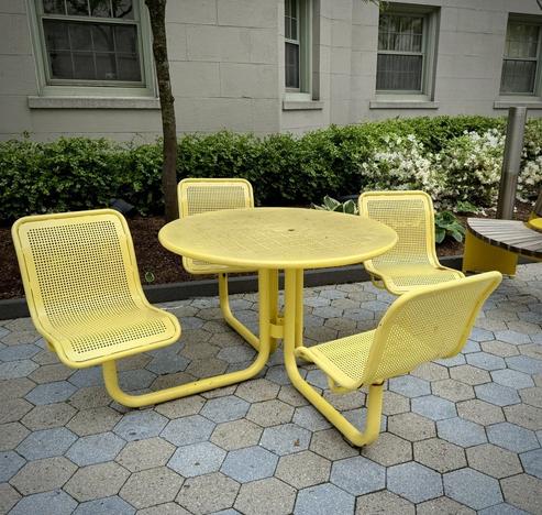 By the Children’s hospital, a metal table where each of the four legs splay out and then has a metal swivel chair on it, so the whole thing is one unit, painted in a bright yellow.