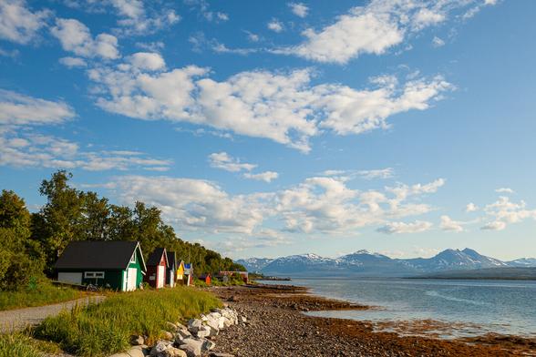 A row of brightly colored boathouses along a beach on the Norwegian island of Tromsø.