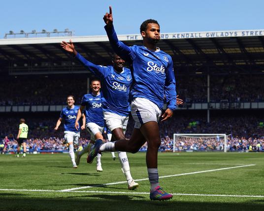 Four Everton players running in a line the front two with an arm outstretched celebrating, in front of Gwladys Street. Photo stolen from The Guardian.