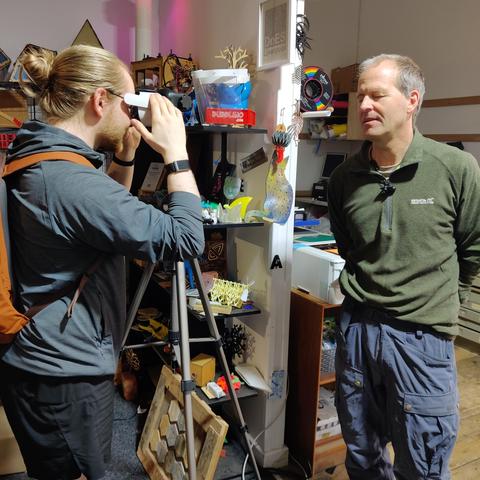 Julian showing a Repair Café visitor how to use a VR headset