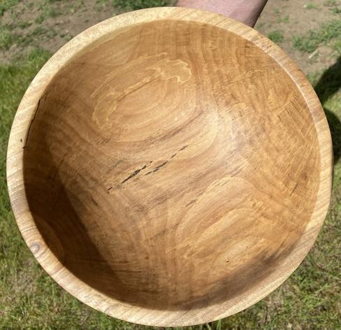 A wooden bowl, seen from above, showing dark grain patterns.