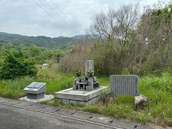Grave, stone obelisk with offerings of food and beer.