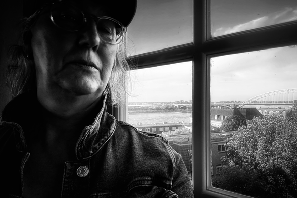 Self-portrait in front of a window at dusk, with the Waal Bridge of Nijmegen out of the corner of my eye.