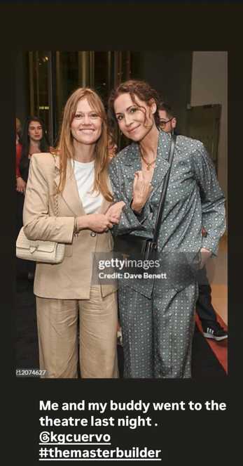Instagram Story with a Getty Images photo of Minnie Driver and a friend at the opening night party for the play “My Master Builder”. They stand with their arms linked, looking at the camera with warm smiles. Minnie wears a loose-fitting, patterned blue pantsuit, and her friend wears a sand-coloured one with a more tailored blazer. Text below the photo reads, “Me and my buddy went to the theatre last night. @ KGCuervo # TheMasterBuilder.”