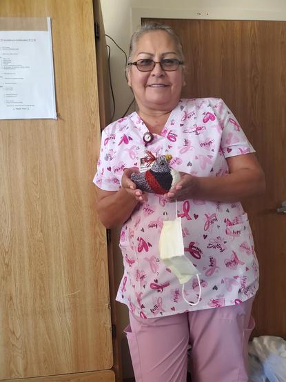 Maranda in pink flowered scrubs holding her black, red and white little chickie