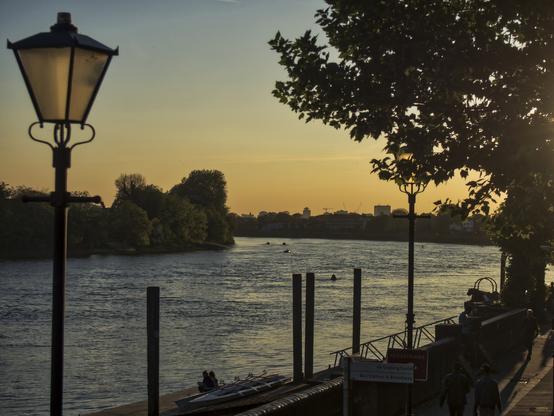 an olde fashioned lamp on one side of a view across a curve in the river , in Sunset light