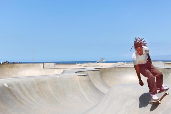 A skater with cool dreads skating inside a pool at the Venice Beach skate park