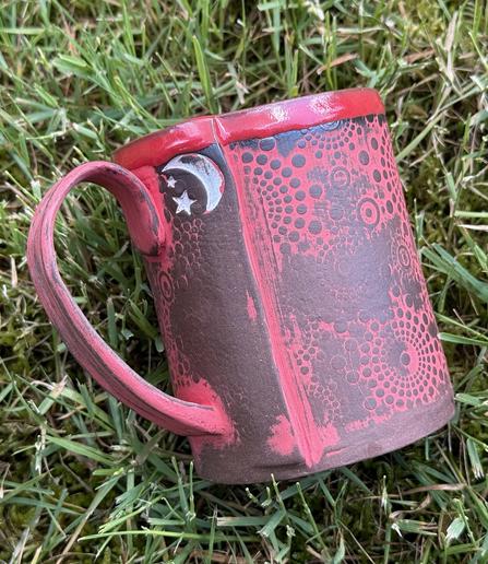 Hand built mug with red underglaze highlighting the texture rolled into the clay.