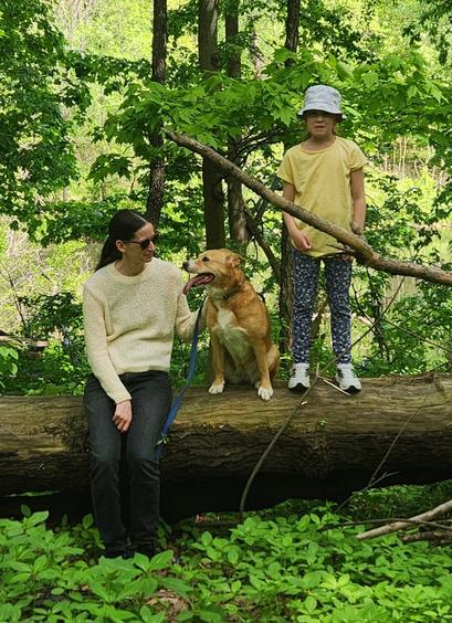 Photo taken in High Park Toronto. My adult daughter is sitting on a large fallen log, Harley, our dog is sitting beside her to the right, and our granddaughter is standing on the log further right.