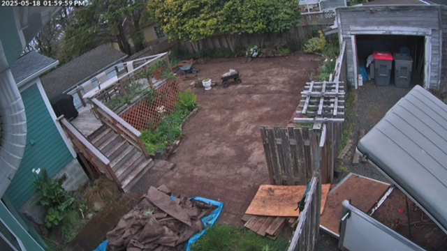 The yard today, mostly bare dirt, but also a pile of old weed cloth on a tarp.  On the right, the open trailer part way through being loaded.