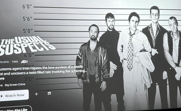 A black-and-white promotional image for the movie "The Usual Suspects." It features five men standing in a police lineup format, with height markers in the background. The movie's title and a brief description about the plot are displayed at the bottom