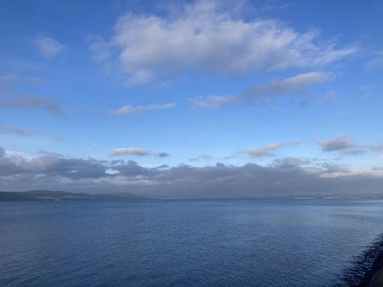 Early morning view across Tay Firth the water is just a soft ripple with the hills variously lit by the sun lighting and hidden by the rolls of cloud