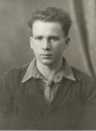 Fotografenbild in schwarz-weiß. Ein junger Mann mit hoher Stirn, lockigen, zurückgekämmten Haaren in einem Kurzhaar-Schnitt, an den Seiten kürzer, oben voll. Er blickt ernst in die Kamera und trägt ein dunkles Sakko, ein dunkles Hemd aus dickerem Stoff, der Kragen liegt auf dem Sakko, der oberste Knopf ist offen. Eine Krawatte trägt er trotzdem. Sie hat ein gleichmäßiges Muster.
Quelle: https://frankfurter-personenlexikon.de/node/3441