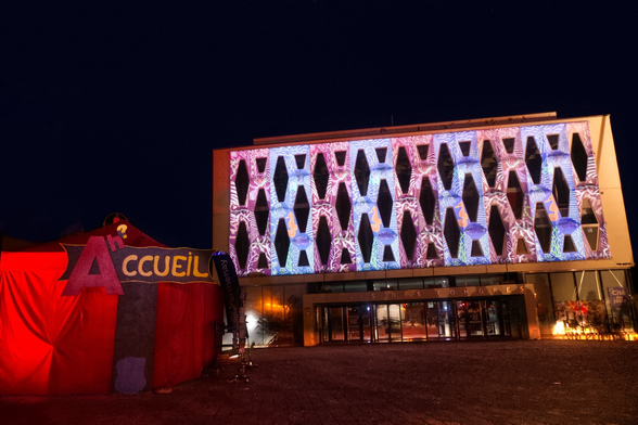 Projection d’illustrations sur un bâtiment année 80 devant une tente rouge