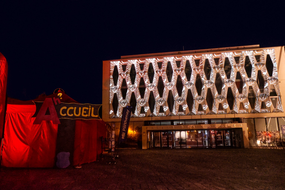 Projection d’illustrations sur un bâtiment année 80 devant une tente rouge