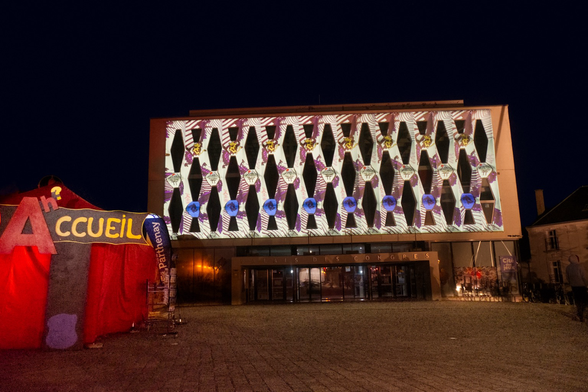 Projection d’illustrations sur un bâtiment année 80 devant une tente rouge