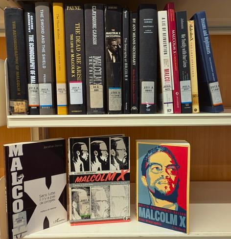 2 bookshelves filled with books on and by Malcolm X