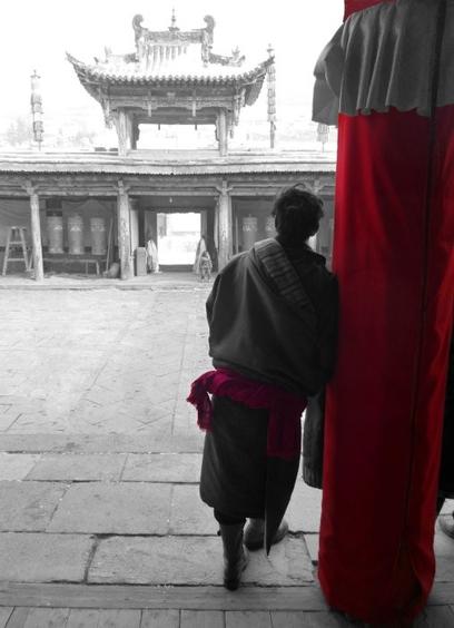 A man is waiting in a Tibetan monastry for something. Selected color red.