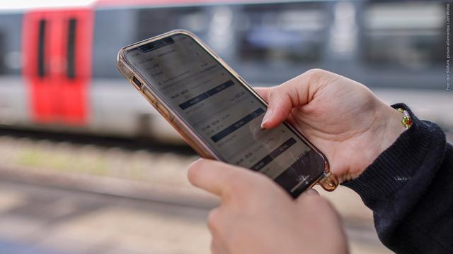 Eine Frau steht mit ihrem Mobiltelefon und der App DB-Navigator auf einem Bahnsteig. Am 19. Mai 2025 wird das Landgericht Frankfurt über die Rechtmäßigkeit der Datenverarbeitung in der Bahn-App DB Navigator entscheiden. (Foto: dpa Bildfunk, picture alliance/dpa | Jan Woitas)