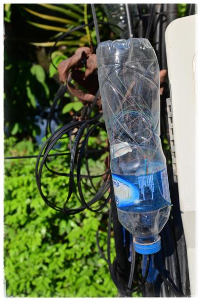 A upside down pet bottle holds a number of fine wires. A cable goes from the bottle and merges into a bunch of other cables.
