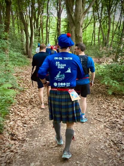 Me on trail, running in my interpretation of Tintin in the album “The Black Isle”, or as it’s called in Gaelic “An T-Eilan Dubh”
A kilted runner seen from the back, wearing a blue balmoral bonnet with a red toorie, and a long-sleeved running shirt with on the back printed “On On Tintin”, “An T-Eilan Dubh”, and Tintin on a boat sailing towards a castle on a rock.