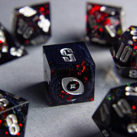 Zu sehen ist ein D6 mit schwarzen swirls. Die Swirls sind von roten Metallflakes und Glitter umgeben.

Die Nummern sind silber geinked. Die Zahl 6 wurde durch mein Logo, ein Auge mit Stern, ausgetauscht.