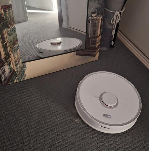My roborock approaching a large mirror leaning against a cabinet