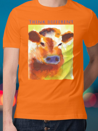 Un tee-shirt unisexe orange illustré par un dessin @itkacreations représentant une vache orange avec le museau violet. La phrase "think different" est facultative est peut être remplacée.