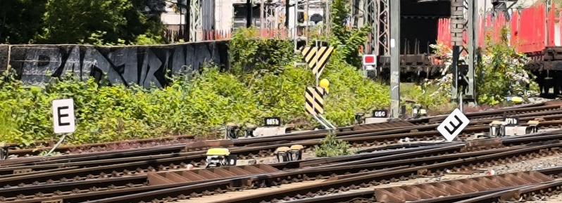 2manuell angebrachte weiße Tafeln an der Schiene mit großem E,veines davon verdreht, sodass das E auf dem Kopf steht