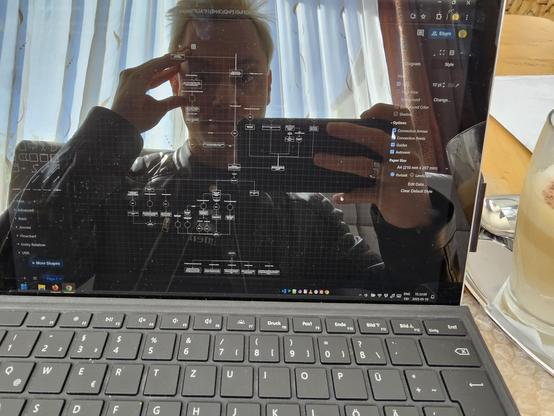 Photo of my Surface Tablet next to a latte. Reflected is my distraught face that blends into the displayed flowchart on screen.