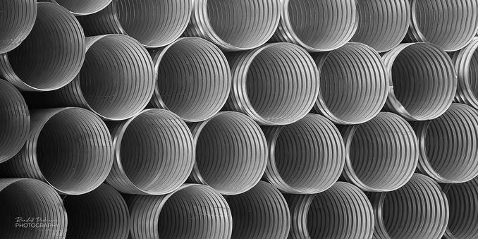 rows of stacked corrugated metal pipe.