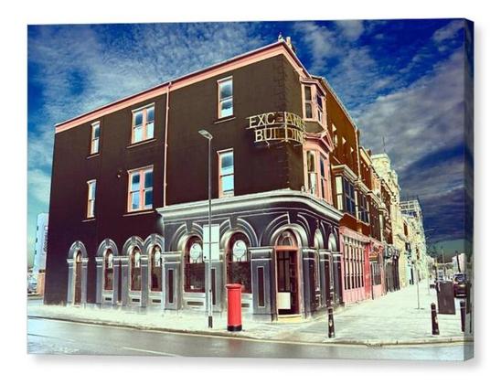 Colour modified photograph showing a high street corner property with a pillar box out front.  The image is shown printed upon a box canvas.