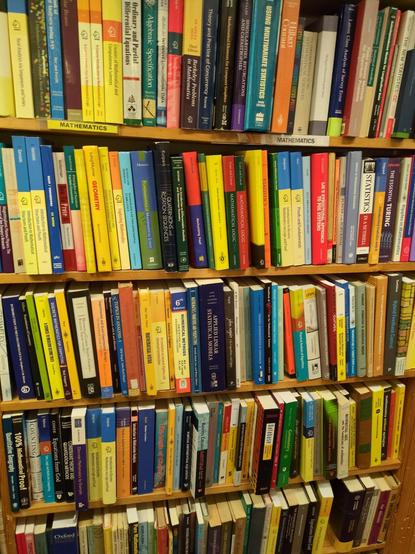 a densely packed shelf of books on math (linear algebra, statistics, algorithms etc, not popsci) looking almost like a university library