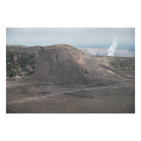 view of a large cinder cone above a solid lava lake with trail worn across
