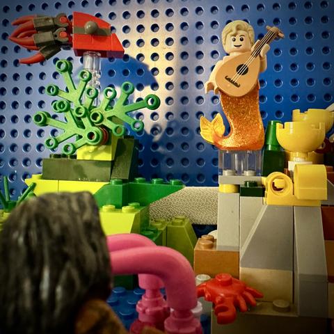 Lego MerStede floating above the reef holding a lute, with Lego MerKraken Ed looking on in the foreground