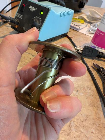 A roll of solder with only a few turns left on it. In the background is a Weller soldering station that is powered on.