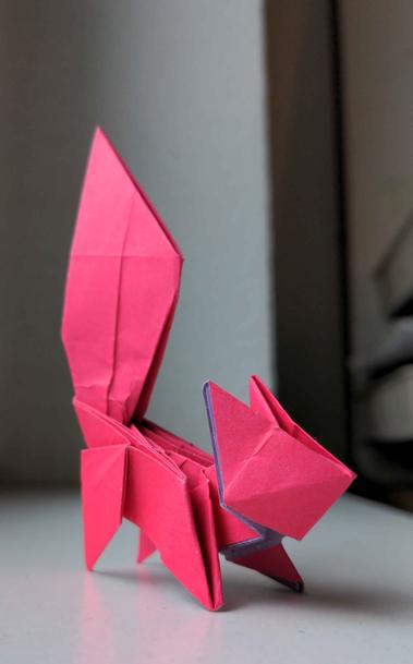 An angular origami squirrel made with hot pink paper.