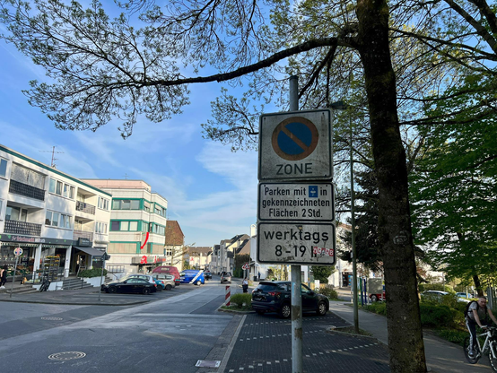 Das Bild zeig die Bergstrasse von oben mit ein paar parkenden Autos links und Rechts. Das alte Parkzone Schild steht im Vordergrund.