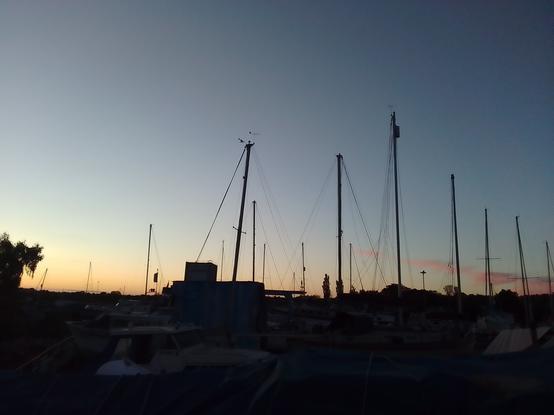 View from the stern looking a bit west of north. A line of small clouds showing pink against the fading blue sky.