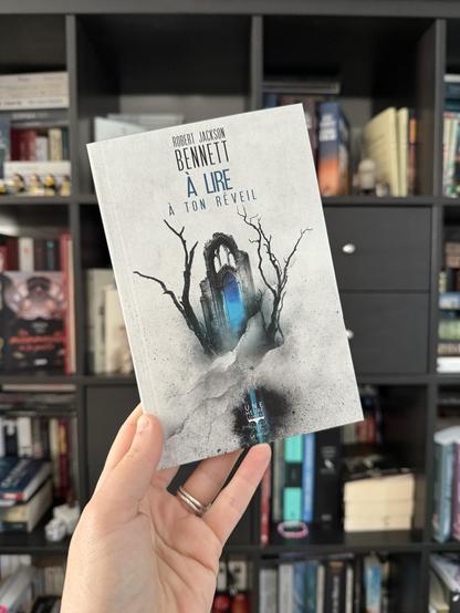 La couverture d’A lire à ton réveil montre un morceau de cathédrale en ruine avec une porte bleue et deux arbres morts sur les côtés.