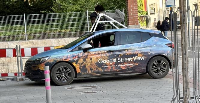Ein Auto mit einem Google Streetview Branding und einem Kameraaufbau auf dem Dach in der Nähe des Augsburger Hauptbahnhofs…