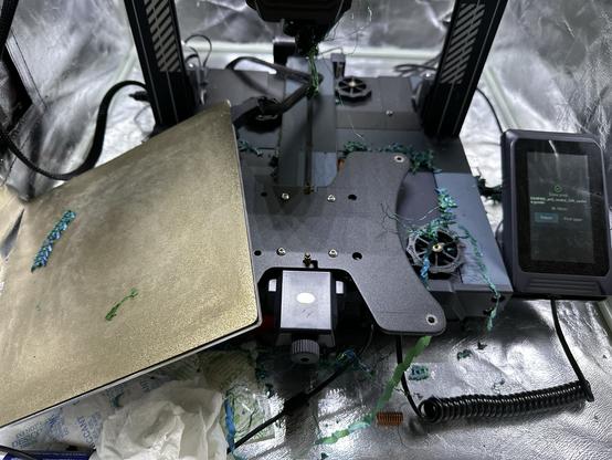 A 3D printer with the bed completely detached, and parts and 3D detritus scattered everywhere.