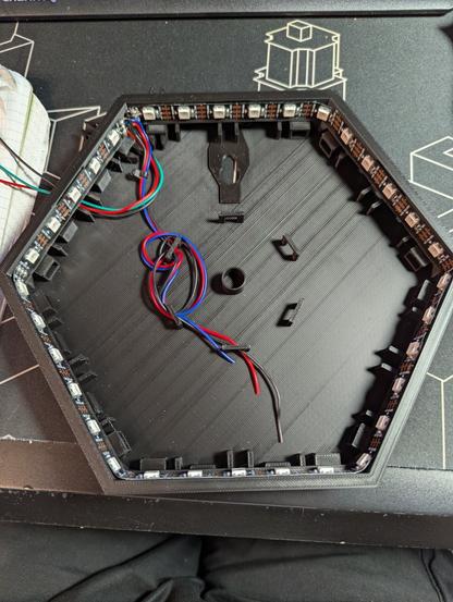 Ein schwarzes, hexagonales Element, welches im inneren mit einem LED-Band beklebt wurde.