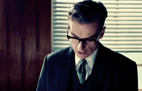 This is a photo of Randall Brown from The Hour. He's dressed in a nice suit with dark-rimmed glasses. His head is tilted down and he's looking at the floor, in thought as he speaks.