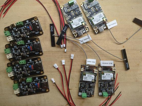 Four MPPT boards sit next to four RAK Wireless LoRa boards, with some unconnected power cords in between. the RAK devices will run Meshtastic.